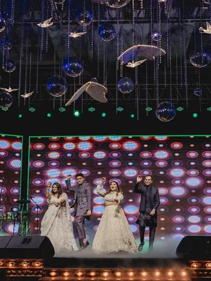 A wide shot of the bride and her brothers' performance, showcasing the grand stage and lighting.
