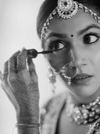 A close-up, candid shot of the bride applying mascara, capturing a real and relatable getting-ready moment.