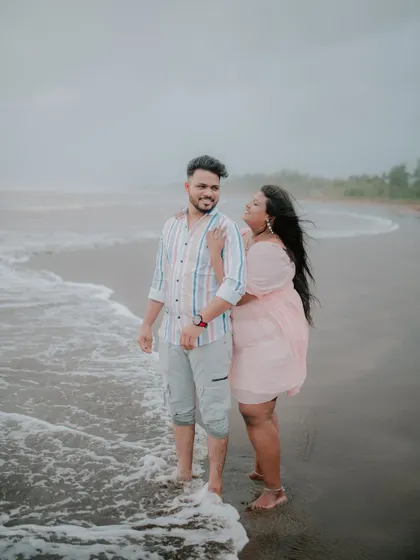 A playful and candid moment between a couple on the beach.