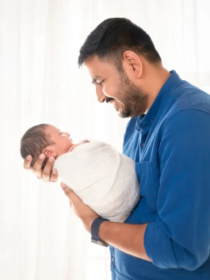 A father's love. A tender moment as a new dad gazes at his peacefully sleeping newborn.