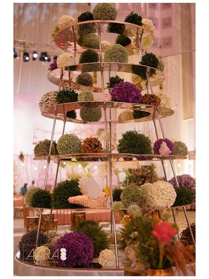 A central floral installation featuring spheres of green and purple flowers arranged on a multi-tiered stand. This unique, Christmas-inspired structure was a modern and artistic focal point for the event.