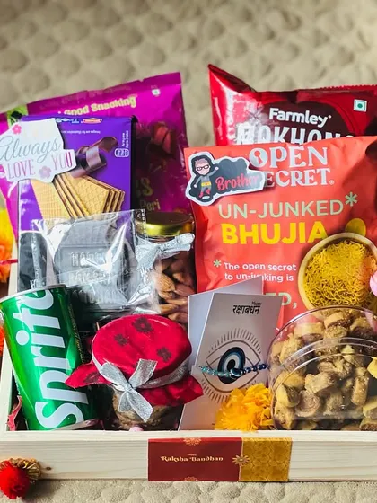A snack-filled Rakhi tray with a mix of chips, biscuits, bhujia, and a drink, perfect for a foodie sibling.