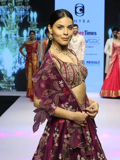 A side view of the pink silk embroidered lehenga from our fashion week collection. The organza cutwork dupatta is designed to look like a cape, adding a touch of drama and modernity.