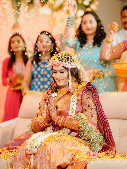 A beautiful bride during her engagement ceremony, being showered with flowers. We designed her intricate floral headpiece and jewellery for this special occasion.