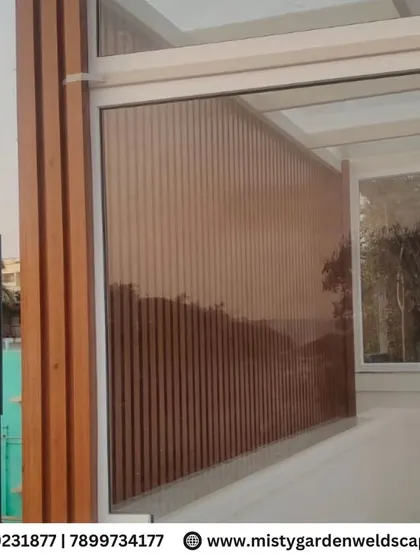 A view of the WPC louvers from the side, showing how they create a solid privacy screen that complements the modern aesthetic of the glass and metal structure.