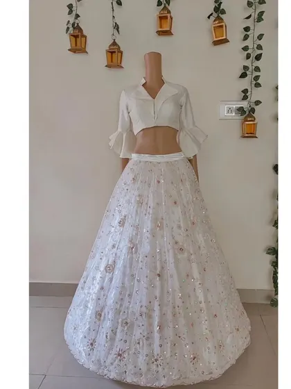 A white Indo-Western lehenga with a modern collared blouse. The skirt is made of a delicate, sequined net fabric.