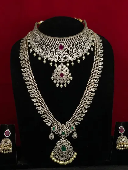A complete bridal set featuring a CZ choker and a long haram with emerald accents. This is a perfect combination for a grand reception.
