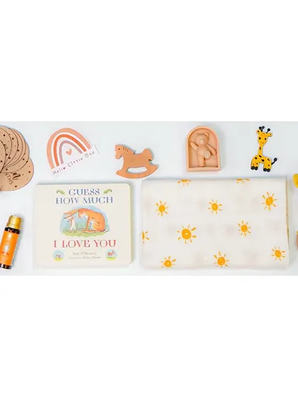 A wide banner-style flatlay of baby gift items on a white background. This 'knolling' style is great for showing the contents of a gift set in a single, clean image.