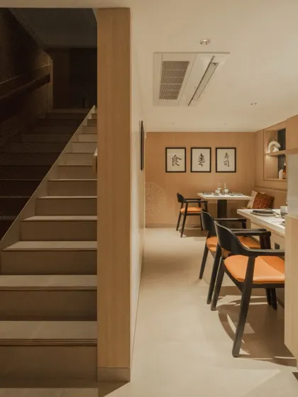 A view of the lower dining level and the simple, clean staircase that leads to the upper floor, all unified by the warm wood paneling.
