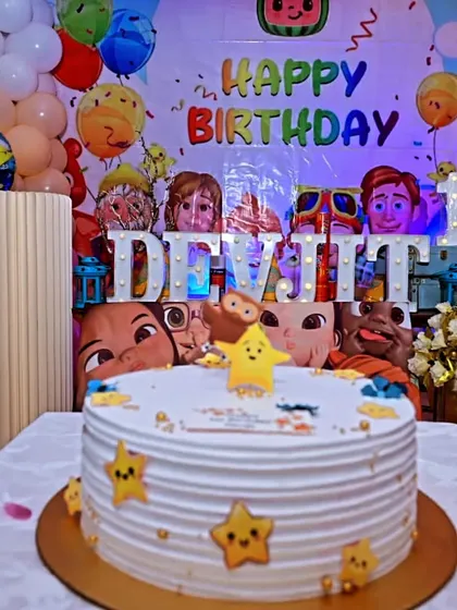 A colorful Cocomelon first birthday party at home. The setup includes a themed cake, a light-up name, and a backdrop featuring all the favorite characters, proving you can have a grand celebration in any space.