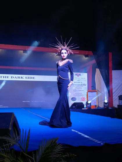 A model in a dramatic black mermaid gown with an elaborate headpiece, showcasing avant-garde fashion.