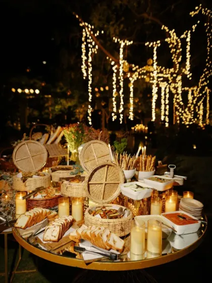 An elegant bread and cheese station for the welcome dinner, illuminated by candlelight. The presentation is rustic yet sophisticated, fitting the warm and intimate theme.