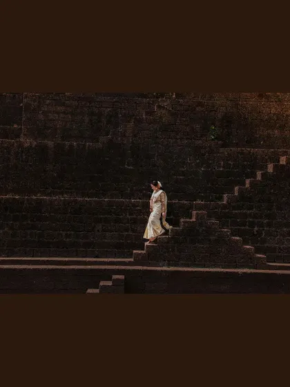 A dramatic shot of the bride descending a large stone staircase.