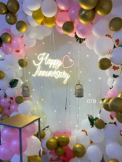 A closer look at the anniversary ring backdrop, showing the details of the balloon arrangement and the hanging birdcage props that add a whimsical touch to the celebration decor.