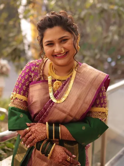 A close-up portrait of the bride, her happy smile capturing the joy of the day. The traditional gold necklace and nath complete her classic Maharashtrian bridal look.