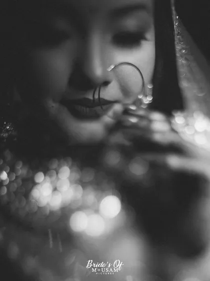 A close-up, black and white portrait focusing on the bride's nose ring and the beautiful bokeh from her necklace. This artistic shot is all about mood, texture, and fine art details.