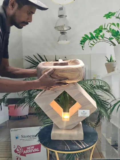 An artisan places the top bowl of the lamp fountain, showing its two-part construction. This lightweight piece is easy to set up and move.