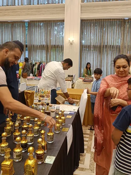 A family explores a stall of luxury fragrances, with the vendor guiding them through the different scents.