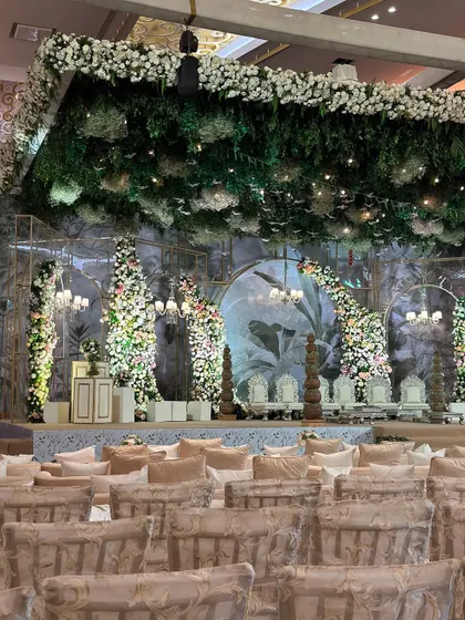 A wide view of the vintage garden setup, with a lush green floral ceiling and elegant seating arrangements. The entire space is transformed into a timeless, romantic oasis.