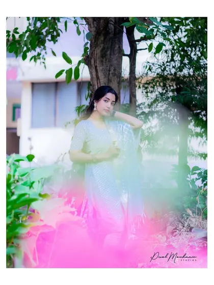Using a creative foreground blur with pink flowers, I framed this shot to give it an artistic and dreamy quality, complementing the soft blue of the ethnic suit.