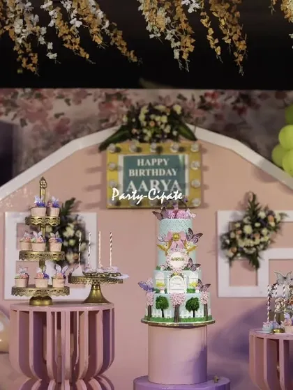 The main stage for Aarya's enchanted forest party. We designed a custom house-shaped backdrop in pink, with floral accents, a beautiful tiered cake, and detailed dessert displays on matching stands.