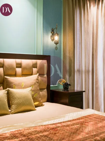 This bedroom design blends elegance and timeless charm. The soft, pastel green wall with classic molding provides a perfect backdrop for the luxurious, textured headboard.