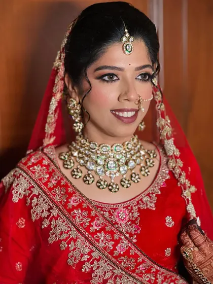 A classic red lehenga look for a beautiful bride. The makeup features a sharp winged liner and a bold lip.
