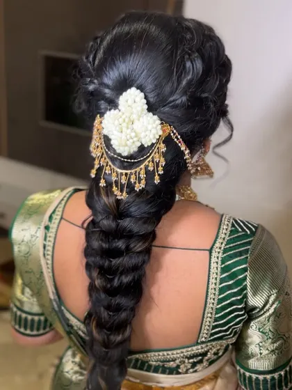 Another angle of this beautiful bridal braid, showing how the floral hairpiece and hanging accessories are placed to create a cohesive and elegant design.