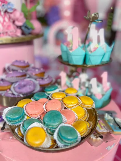 The carnival dessert table included a vibrant assortment of treats, like these colourful handcrafted macarons and mini donuts, all designed to match the party's pastel pink and teal colour scheme.