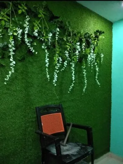 A full view of the artificial grass wall with delicate white hanging flowers. This is a simple and effective way to create a beautiful photo corner or accent wall in any room.