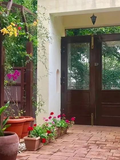 The garden gate at the Roopa Hariprasad Residence is set within a lushly planted entryway. The design of the gate and surrounding brick pathway creates a charming and inviting transition from the public street to the private garden.