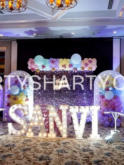This fairy-themed stage features a shimmering silver sequin backdrop, large 3D butterfly wings for photo ops, and marquee letters, creating a glamorous and enchanting focal point.