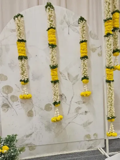 Another detail shot of the flower garlands against the subtle, leafy pattern of the backdrop panels. The combination of fresh flowers and elegant patterns adds texture and depth to the naming ceremony decor.