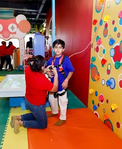 Safety is our priority. Here, a staff member helps a child get securely fastened into a harness for our climbing wall.