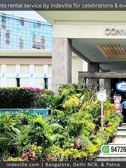 A wide shot of the temporary landscape installation at the Sheraton Convention Center. The dense arrangement of rental plants transforms the modern building's entrance into a tropical oasis.
