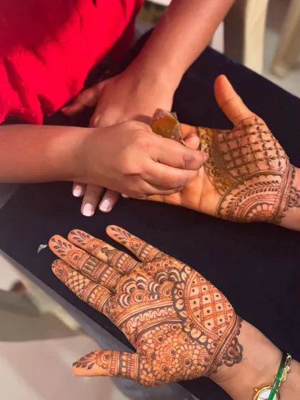 A behind-the-scenes shot of my team member applying mehendi to a guest, showcasing our process for handling larger groups.