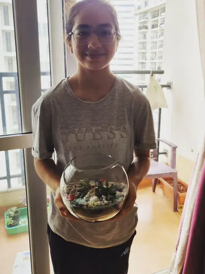 A young participant proudly holding her finished fishbowl terrarium. Each child gets to take home their own unique creation.
