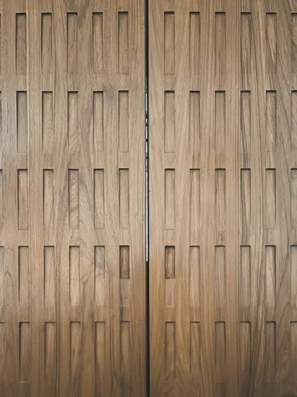 A close-up of custom wooden paneling designed for the Worli duplex. The rhythmic, carved pattern adds texture and a layer of detailed craftsmanship to the interior walls.