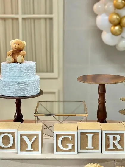 A classic teddy bear theme detail for a gender reveal or baby shower. The simple "BOY GIRL" blocks and a cute teddy bear on the cake create a sweet and timeless look.