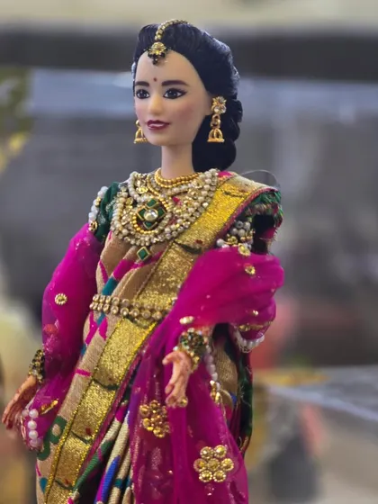 This custom doll is dressed in a stunning pink and green Paithani saree with detailed jewelry. We handcraft every element to match the client's vision.