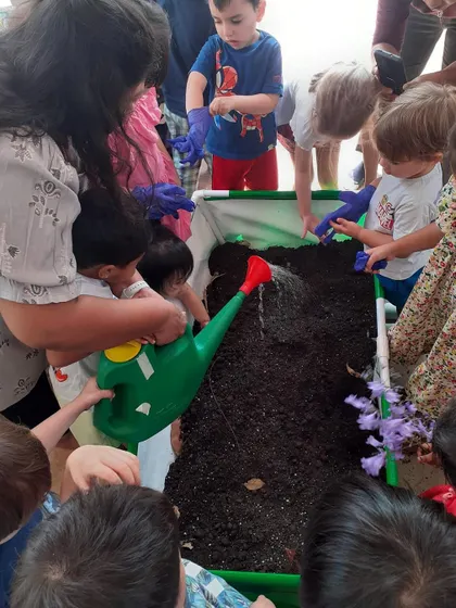 Teamwork in action as children take turns watering the soil in our new garden bed.