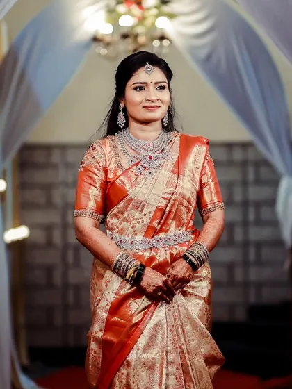 A full view of the bride's reception ensemble. The jewellery is chosen to enhance her natural beauty and complement her gorgeous orange and gold saree.