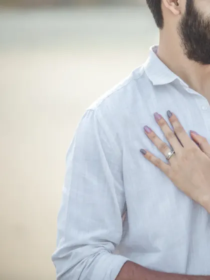 A detail shot focusing on the engagement ring as the bride's hand rests on her partner's chest. It's a subtle yet powerful symbol of their bond.