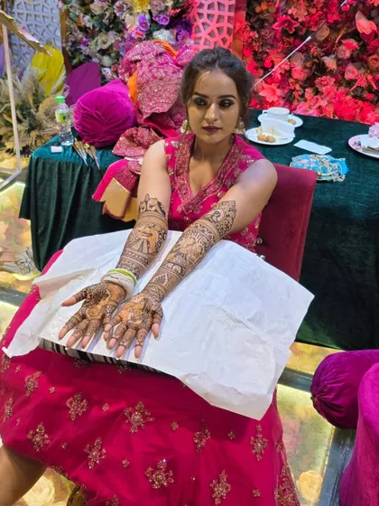 This bride looks absolutely radiant with her completed bridal mehandi. The design features classic portraits and looks stunning against her pink dress.