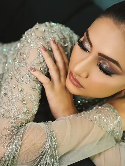 A close-up of the exquisite beading on the silver-grey gown. The sheer sleeves and high neckline add a touch of sophisticated glamour.