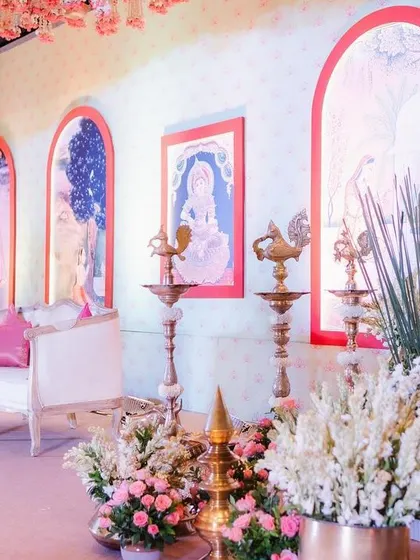 The stage for this half-saree function featured a backdrop with beautiful traditional paintings. These artworks depict the stages of a woman's life, adding a rich narrative layer to the celebration.