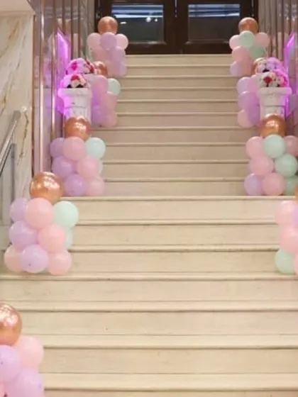 Elegant staircase decoration with pastel balloon pillars topped with rose gold balloons.