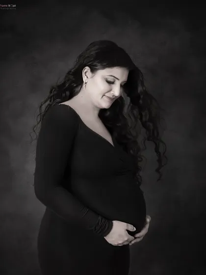 A gentle moment captured in a timeless black and white portrait. The soft light and her downward gaze towards her bump create a feeling of deep love and anticipation.