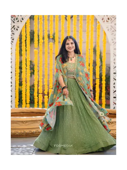 A beautiful portrait of a guest enjoying the Haldi festivities, showcasing the vibrant green attire against a backdrop of marigolds.