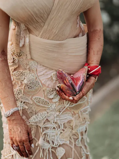 A detail shot of Nikita's welcome lunch look, featuring a unique heart-shaped clutch from Judith Leiber that adds a playful touch to the sophisticated gown.